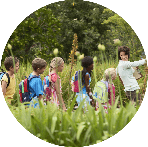 Kid walking in the field with their teacher